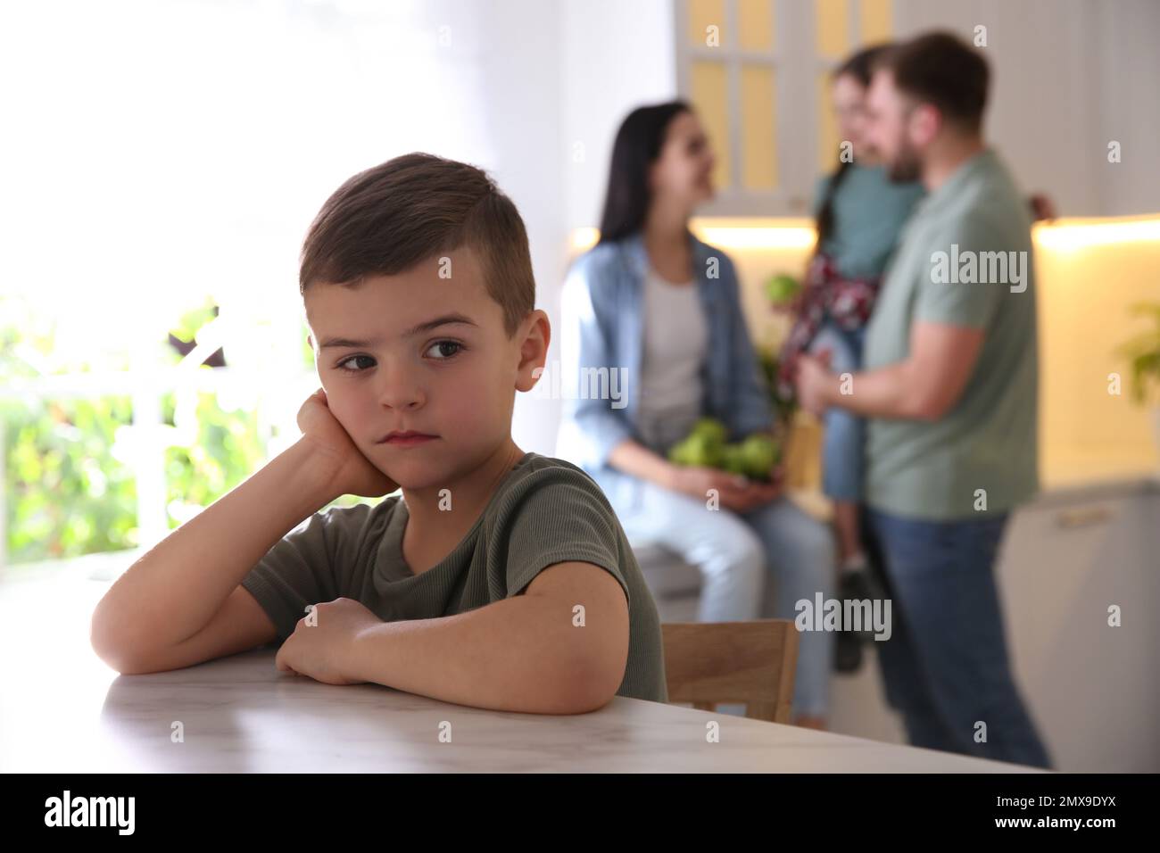 Unhappy little boy feeling jealous while parents spending time with his
