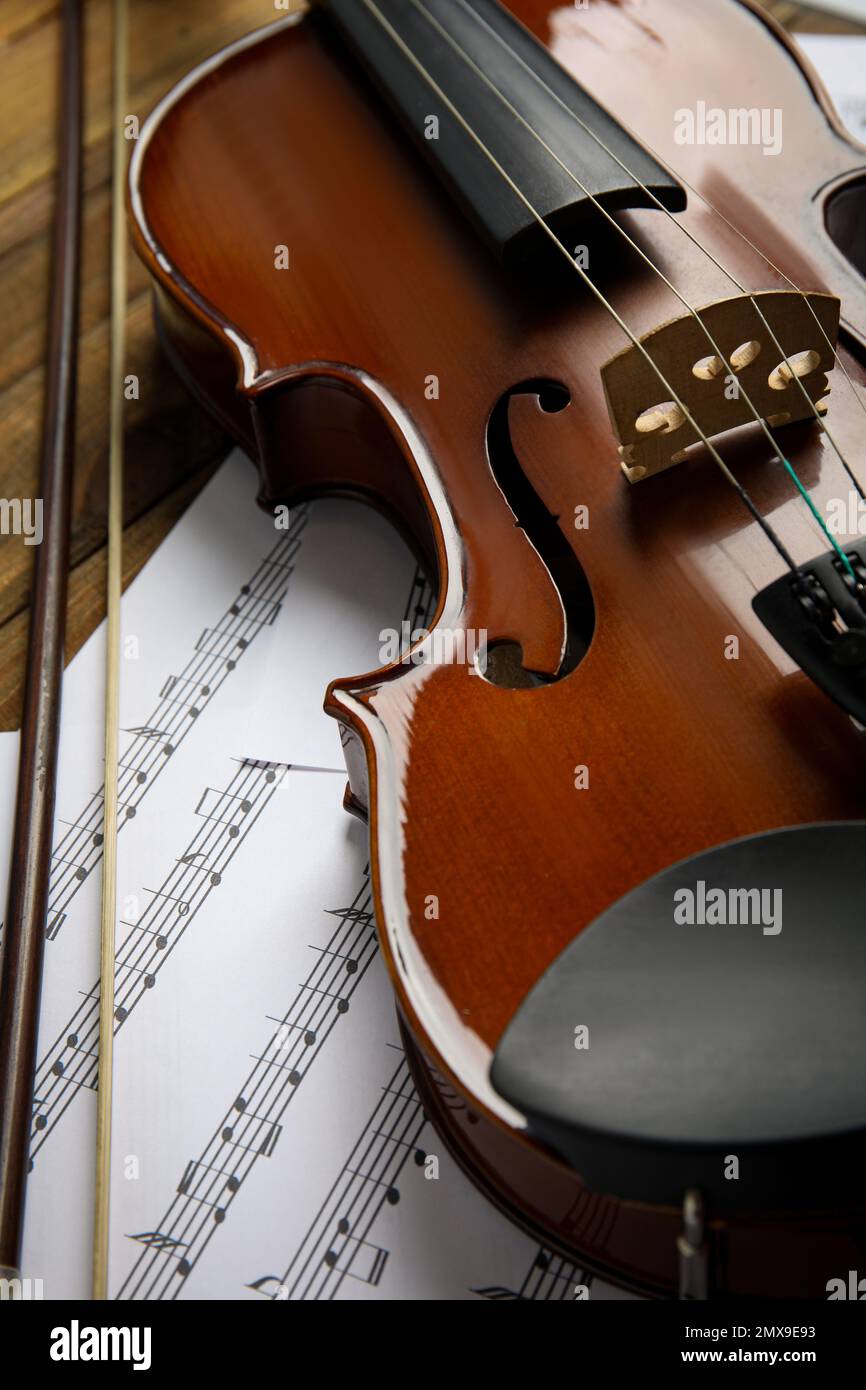 Beautiful violin, bow and note sheets on wooden table Stock Photo
