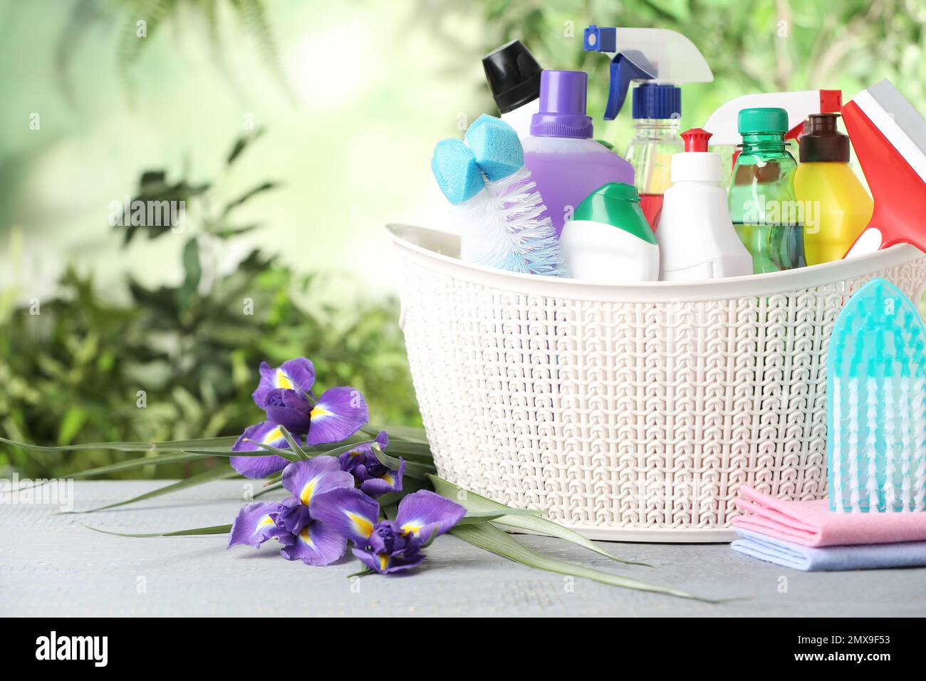 Spring flowers and cleaning supplies on light wooden table Stock Photo