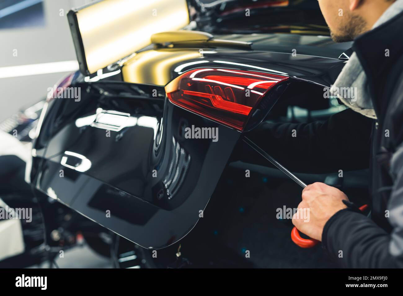 Mechanic and car detailing. Dent removal process from a car trunk