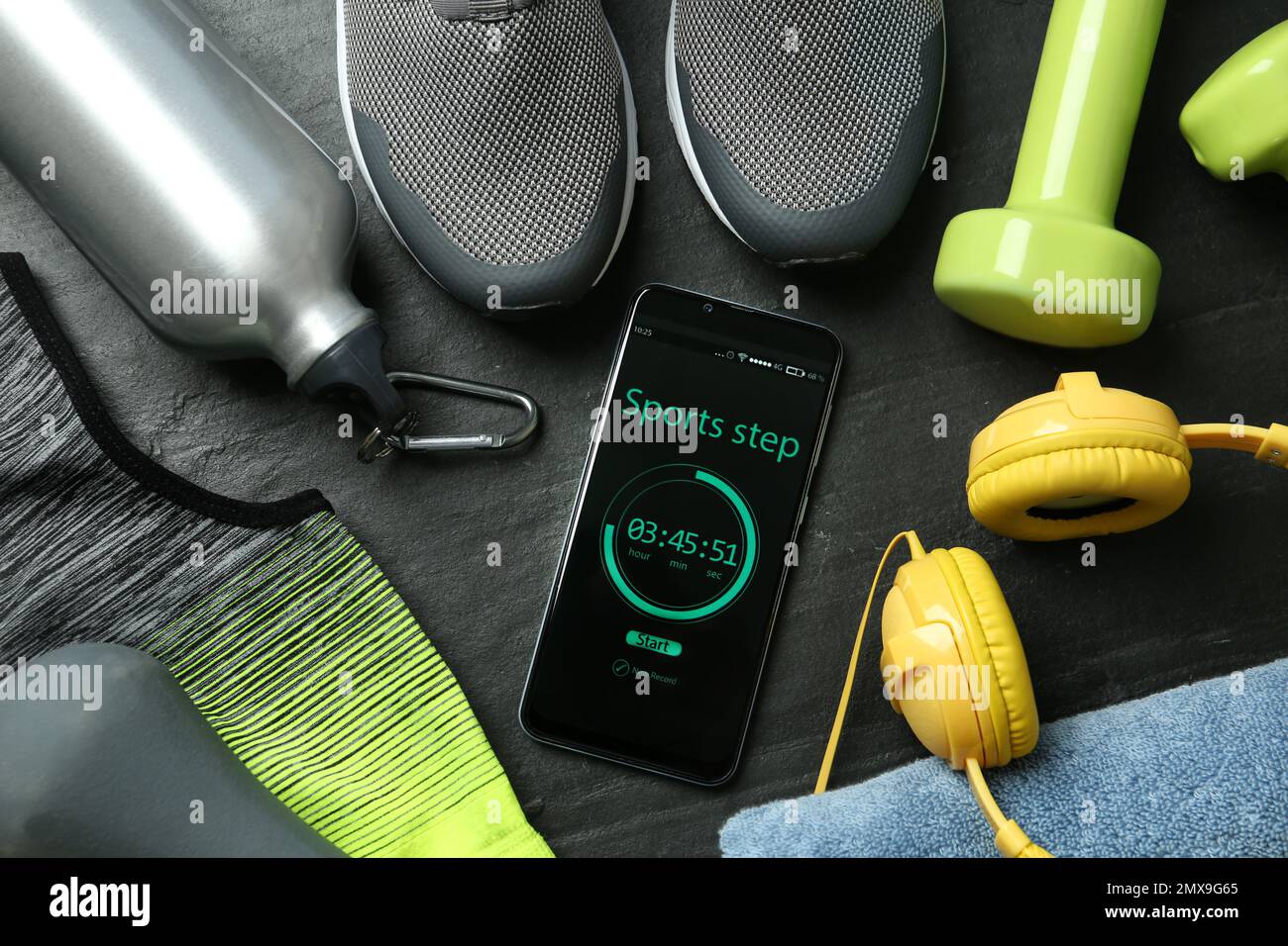 Smartphone with step counter app and fitness accessories on black background, flat lay Stock Photo