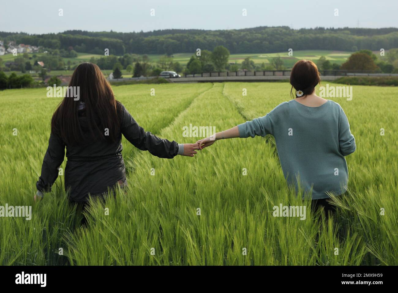Two women striding through corn field and holding hands Stock Photo - Alamy