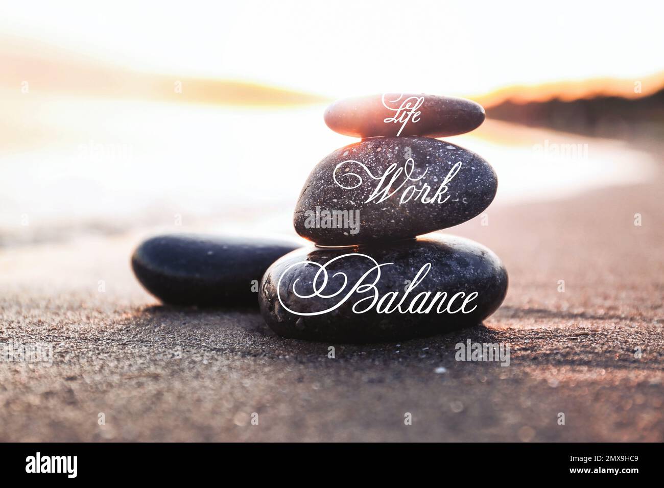 Work-life balance concept. Stacked stones on sandy beach at sunset ...