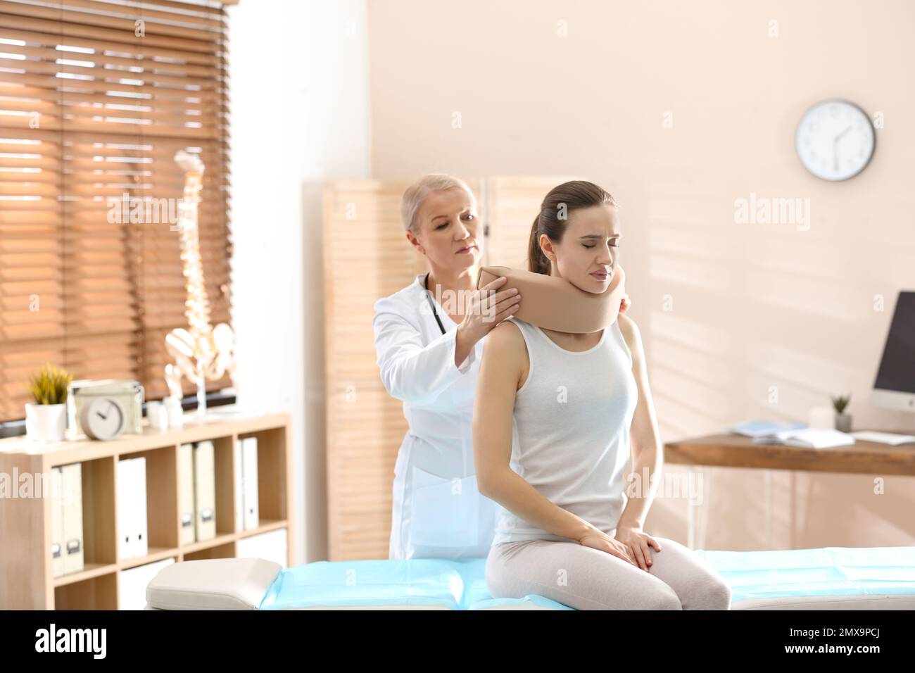 Female orthopedist applying cervical collar onto patient's neck in