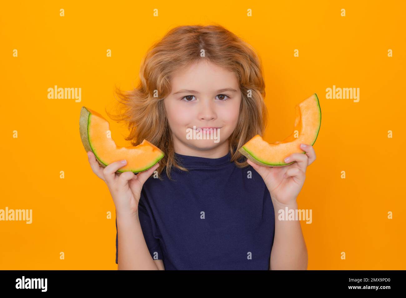 Melon. Child hold red melon in studio. Melon fruit. Studio portrait of cute kid boy with melon isolated on yellow Stock Photo