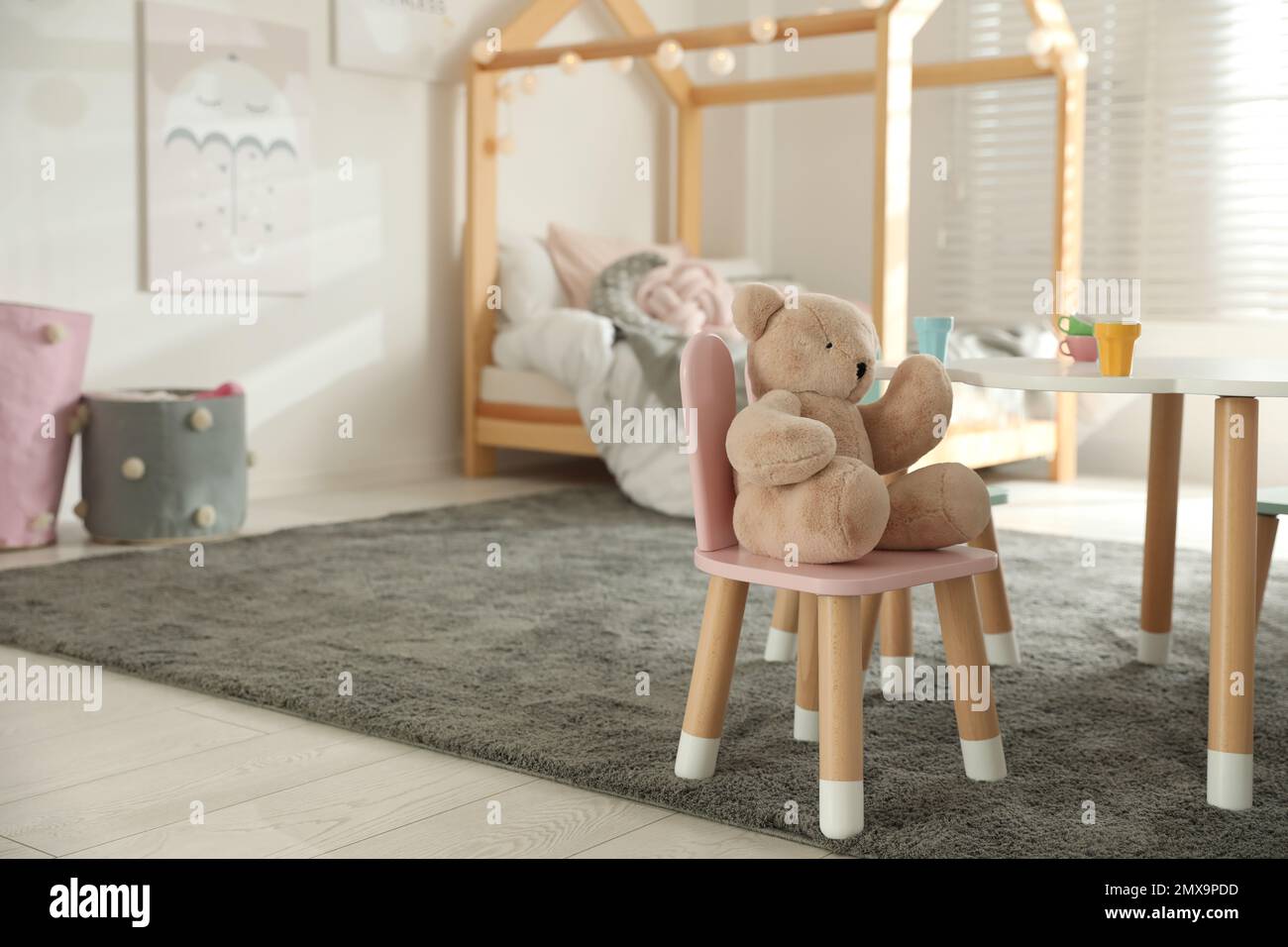 Small table, chair with bunny ears and teddy bear in children's bedroom