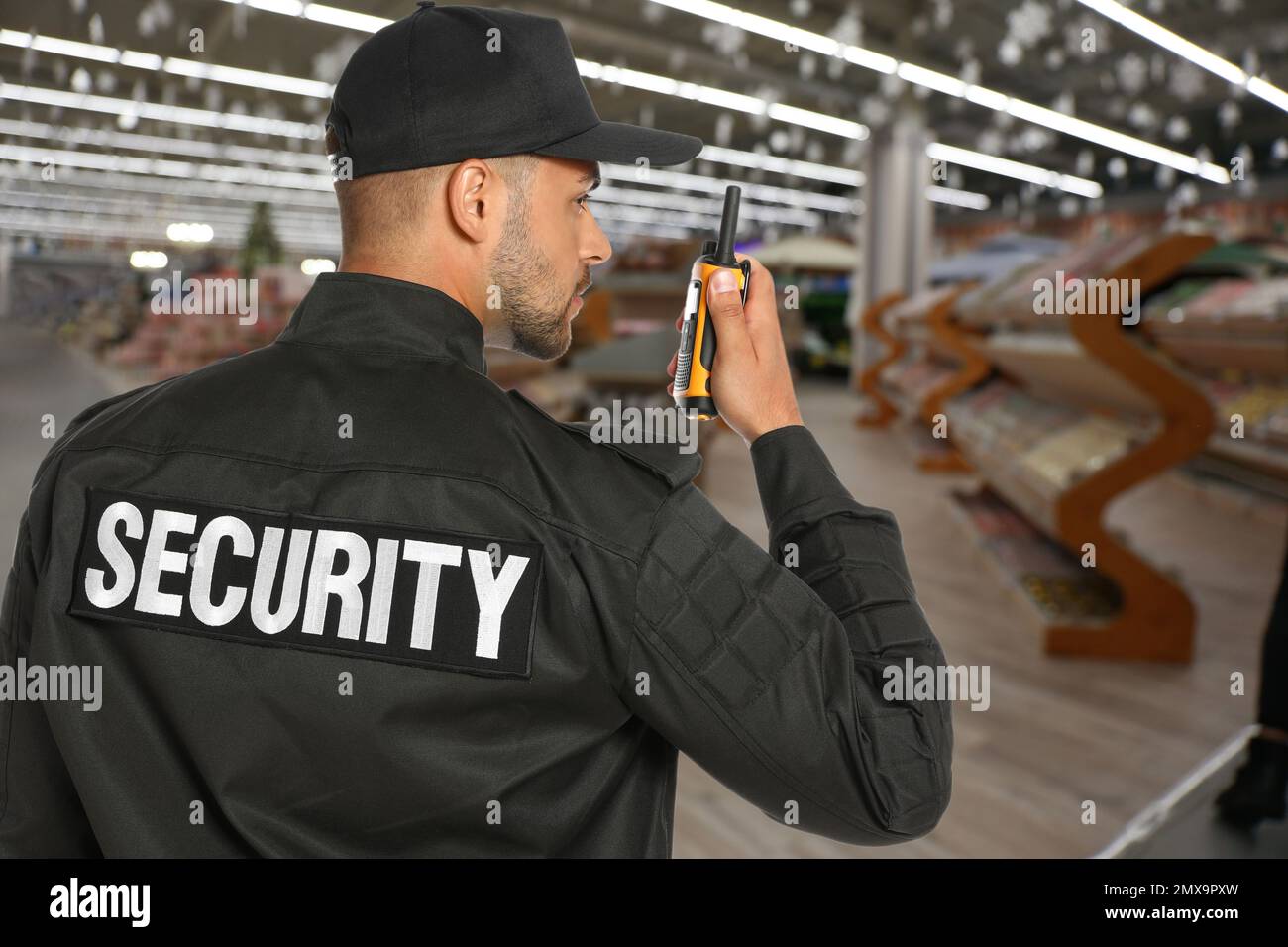 Security guard using portable radio transmitter in shopping mall Stock