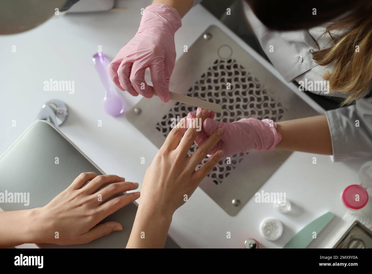 Professional manicurist filing client's nails in beauty salon, top view ...