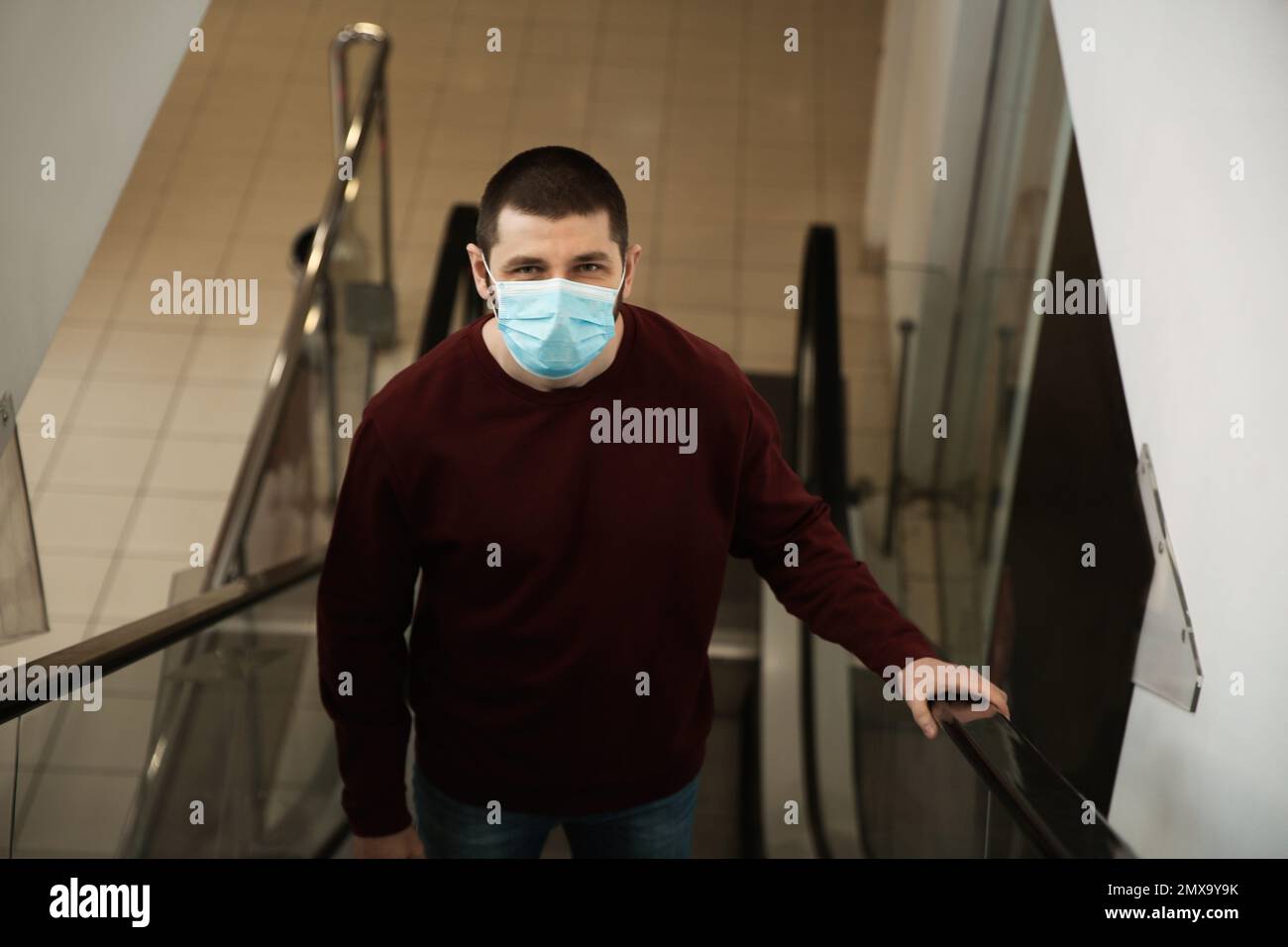 Man with disposable mask on escalator in mall. Dangerous virus Stock ...