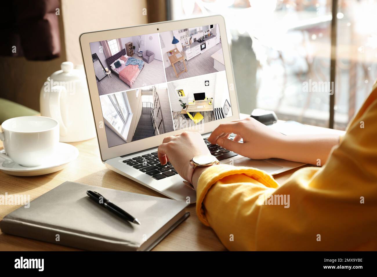 Woman monitoring modern cctv cameras on laptop indoors, closeup. Home security system Stock Photo