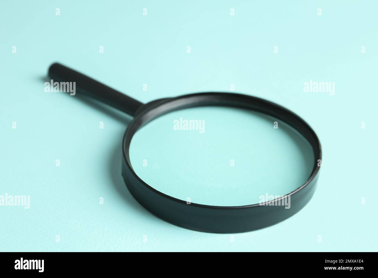 Magnifying glass on light blue background, closeup. Search concept