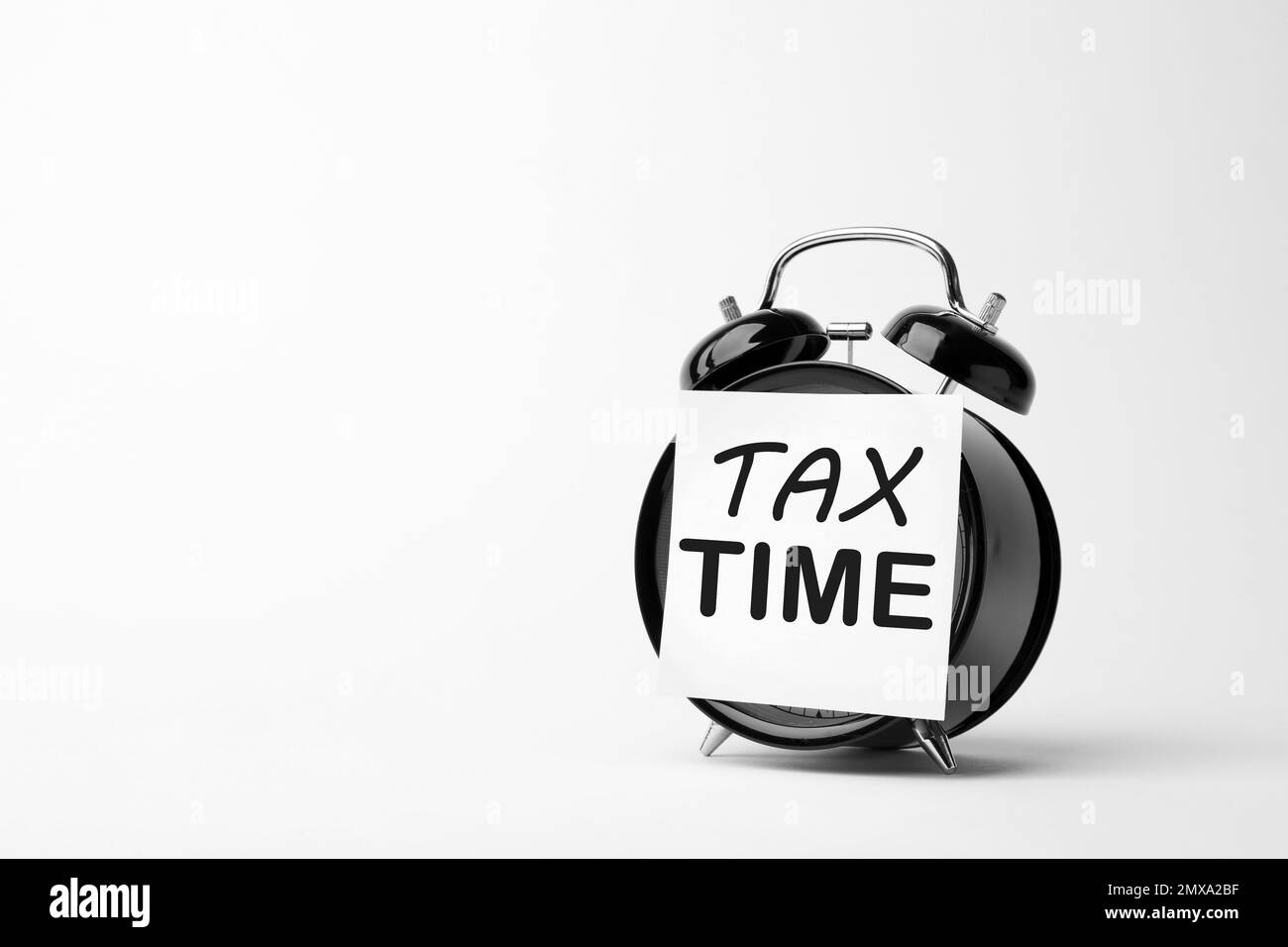 Time to pay taxes. Alarm clock with sticky note on white background Stock Photo