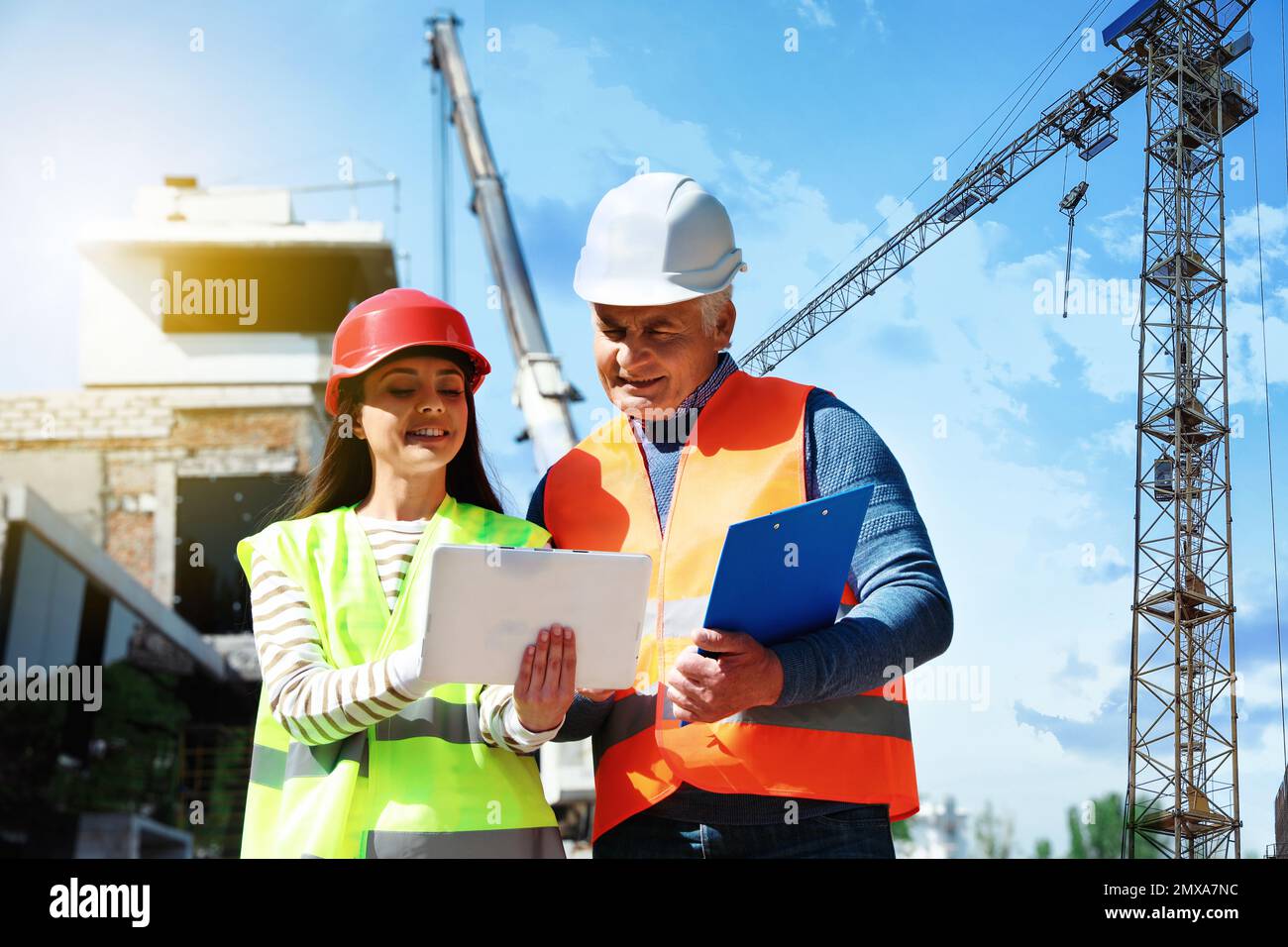 Professional engineer and foreman in safety equipment with tablet at construction site Stock Photo