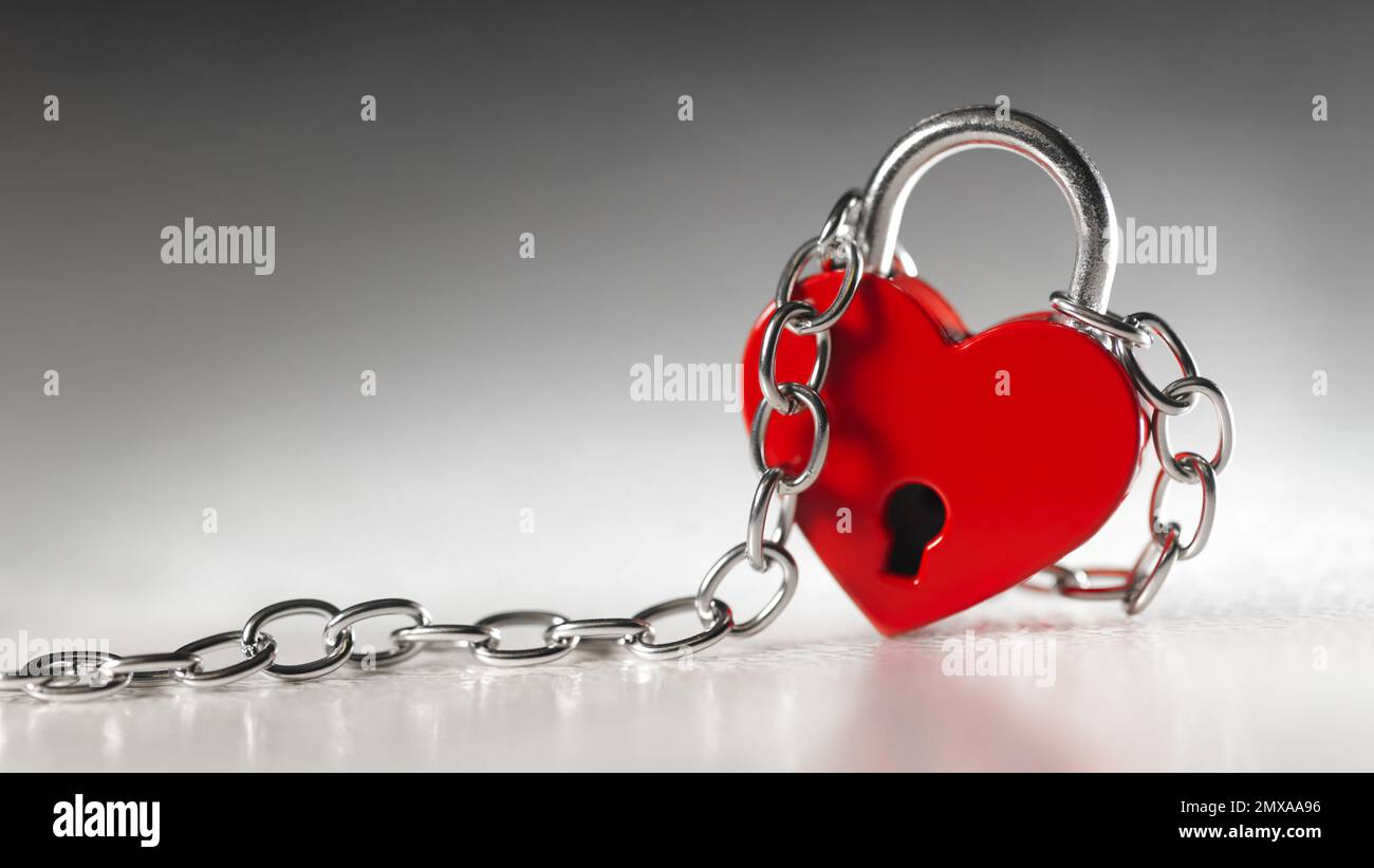 Lock in the shape of a red heart with chains. Love in wedlock, marriage, or Valentine's Day concept. Stock Photo