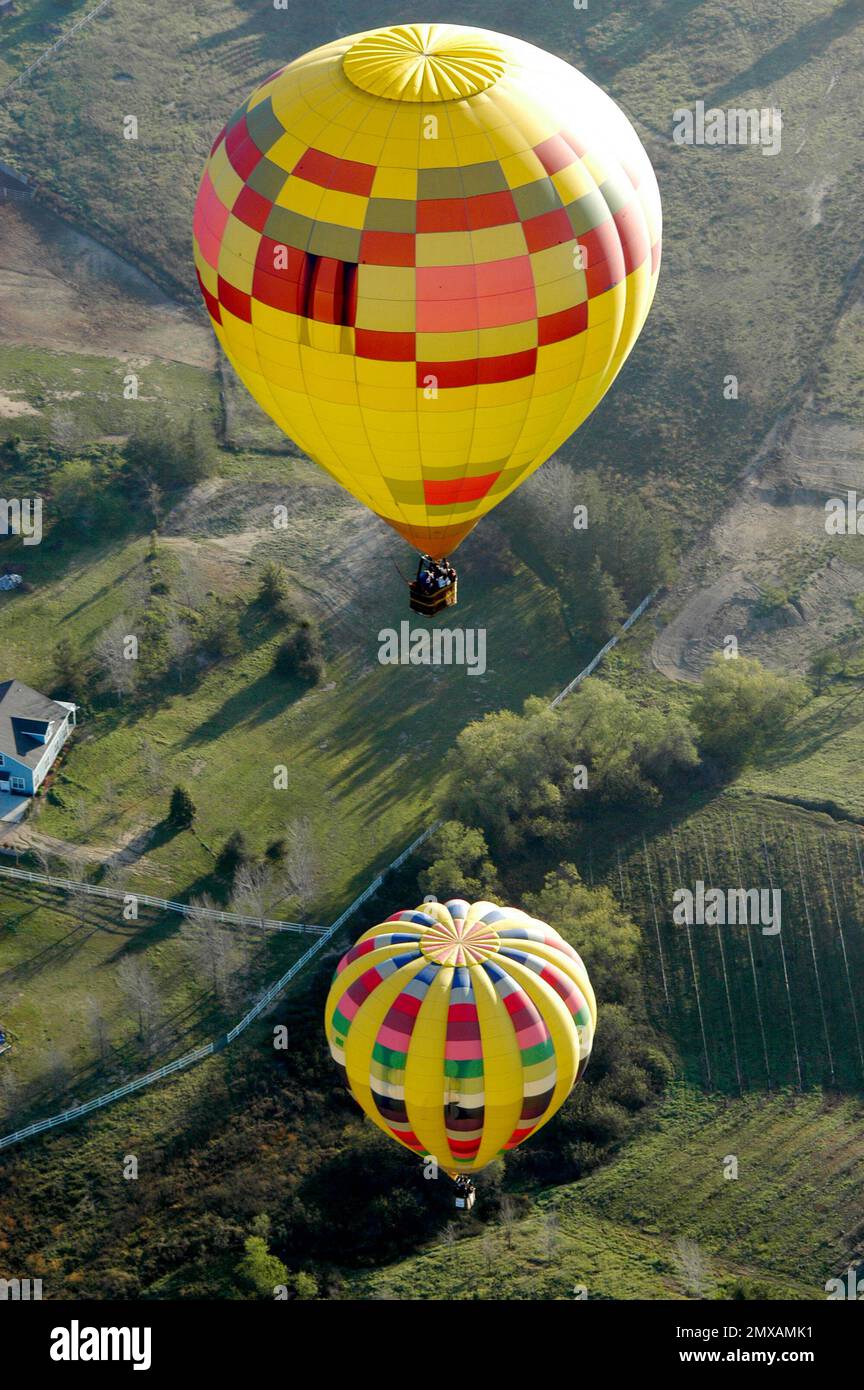 Two hot air balloons flying together over fields in California. Stock Photo