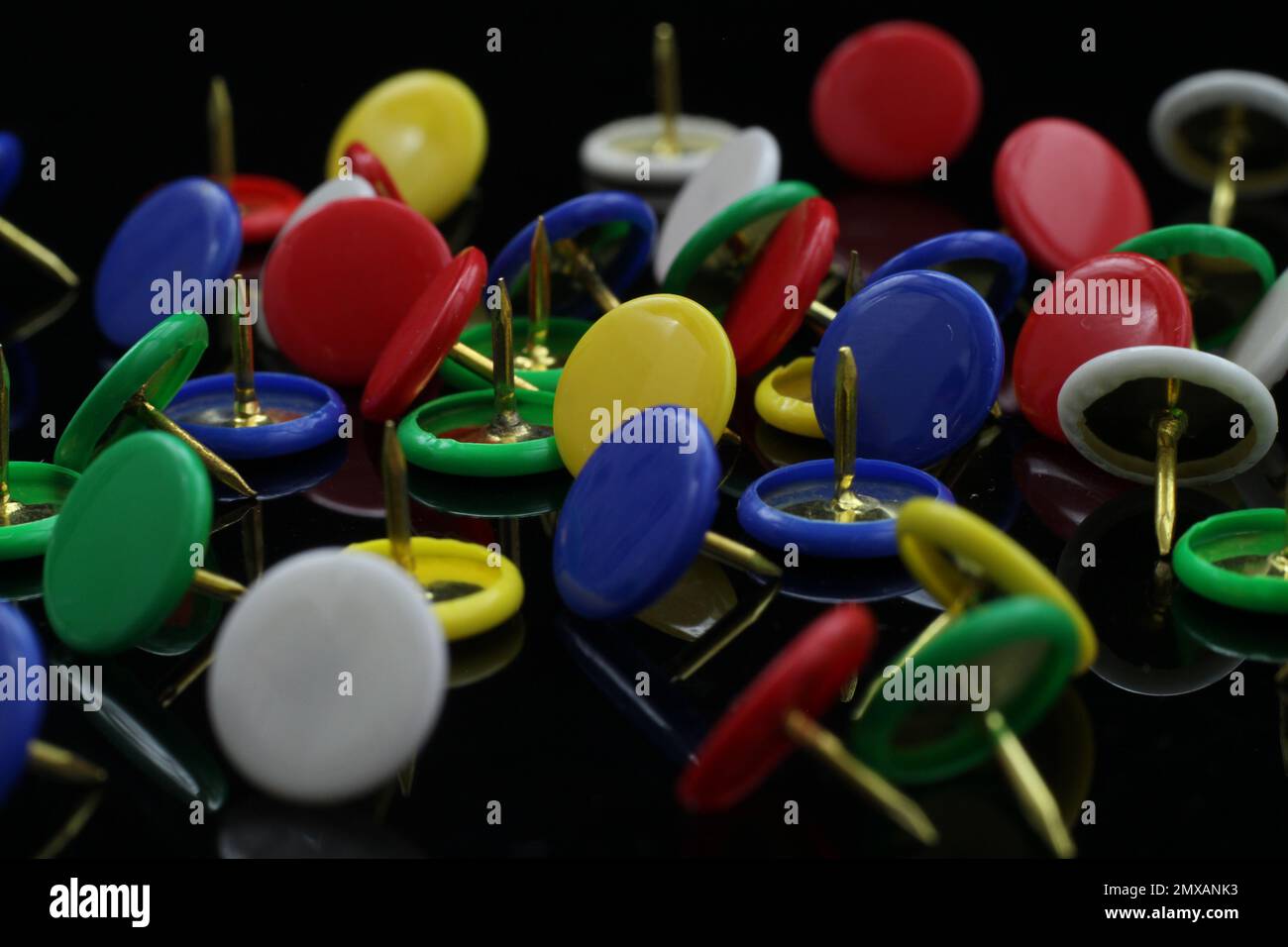 multicolored tacks isolated on black background Stock Photo