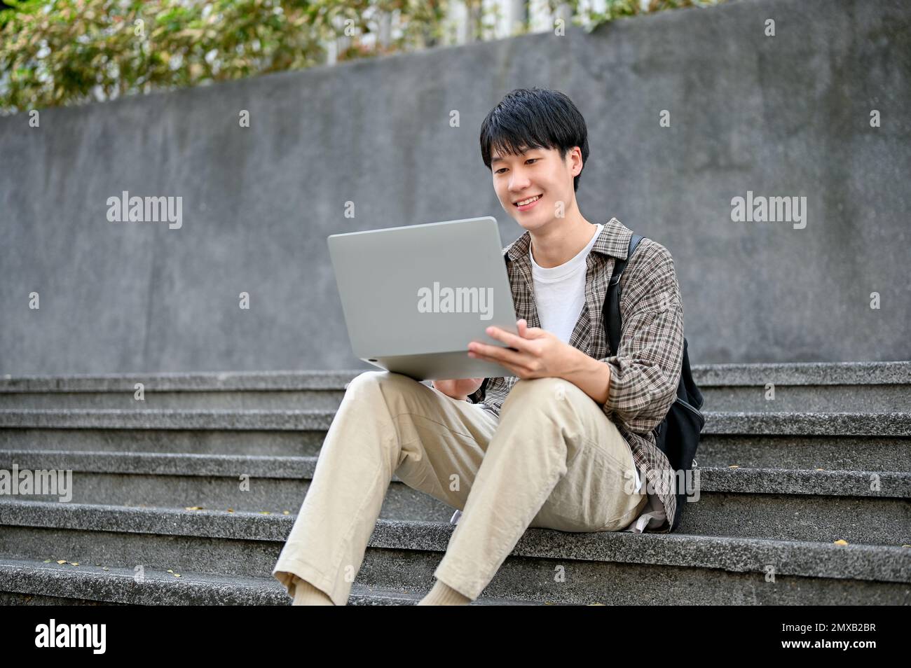 Happy and handsome young Asian male college student in casual clothes ...