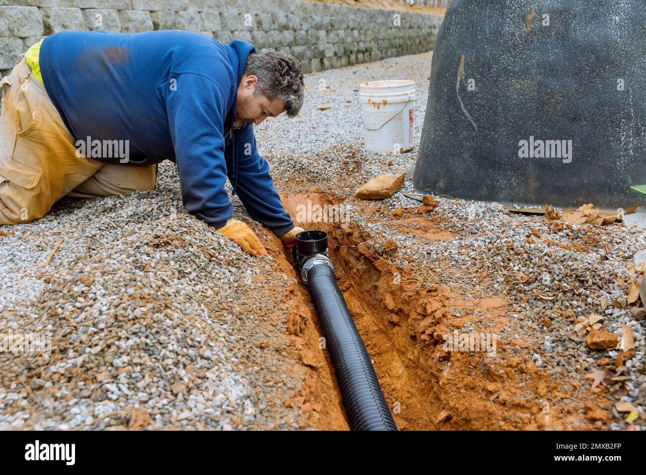 Assembling drainage pipe for rain water that is going to be used for rain water collection on covered parking space with gravel driveway Stock Photo