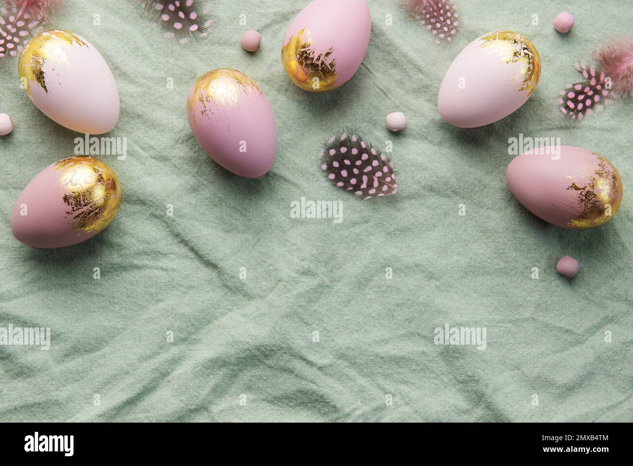 Easter eggs are painted with gold and violet paint on a green linen ...