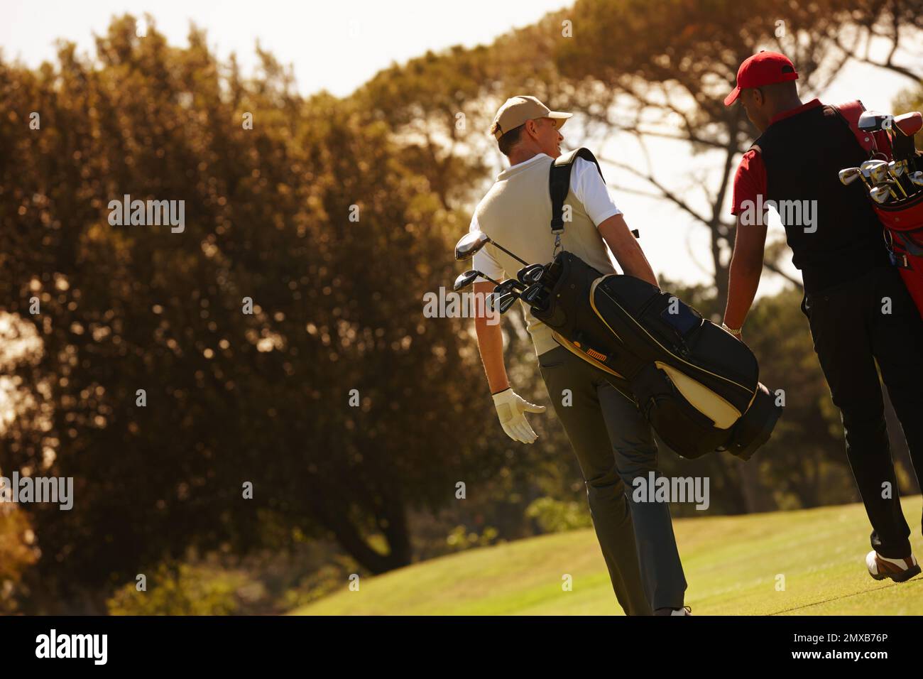 That was the best game of golf weve had. Rear view shot of two men carrying their golf bags across a golf course. Stock Photo