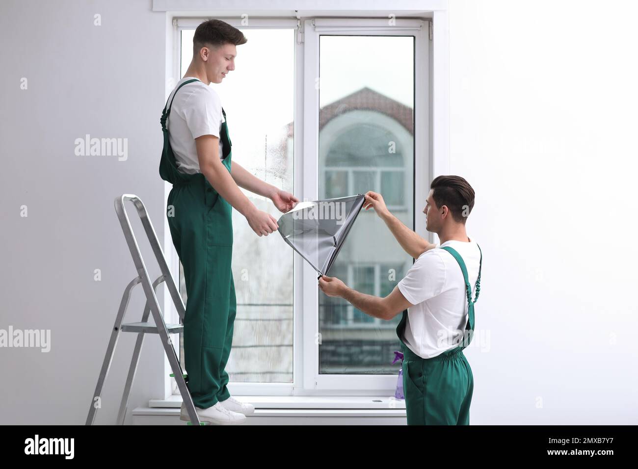 Professional workers tinting window with foil indoors Stock Photo