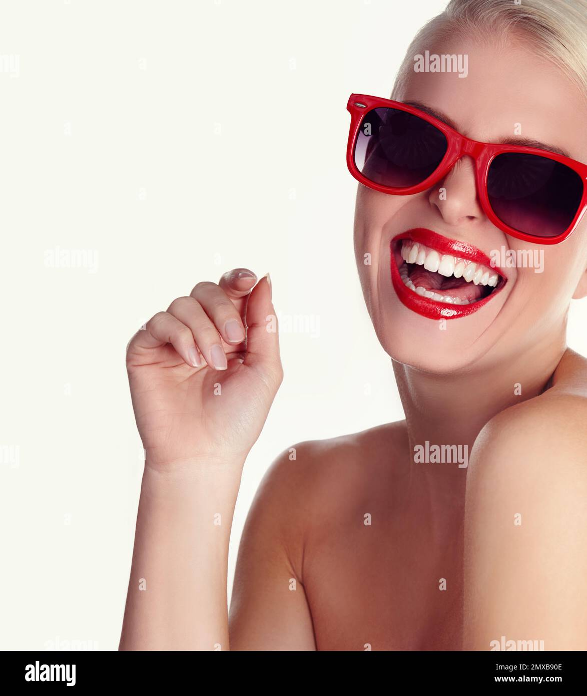 Showing off a Hollywood smile. A laughing blonde wearing red sunglasses against an isolated background. Stock Photo