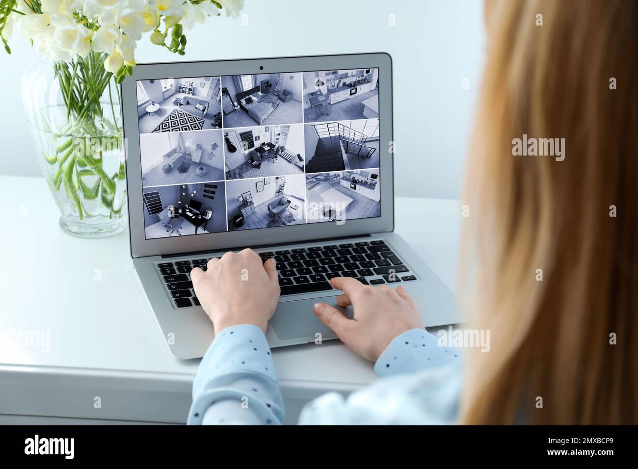 Woman monitoring modern cctv cameras on laptop indoors, closeup. Home