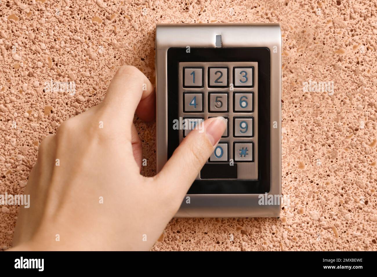 Woman entering code on electronic lock's keypad indoors, closeup Stock Photo