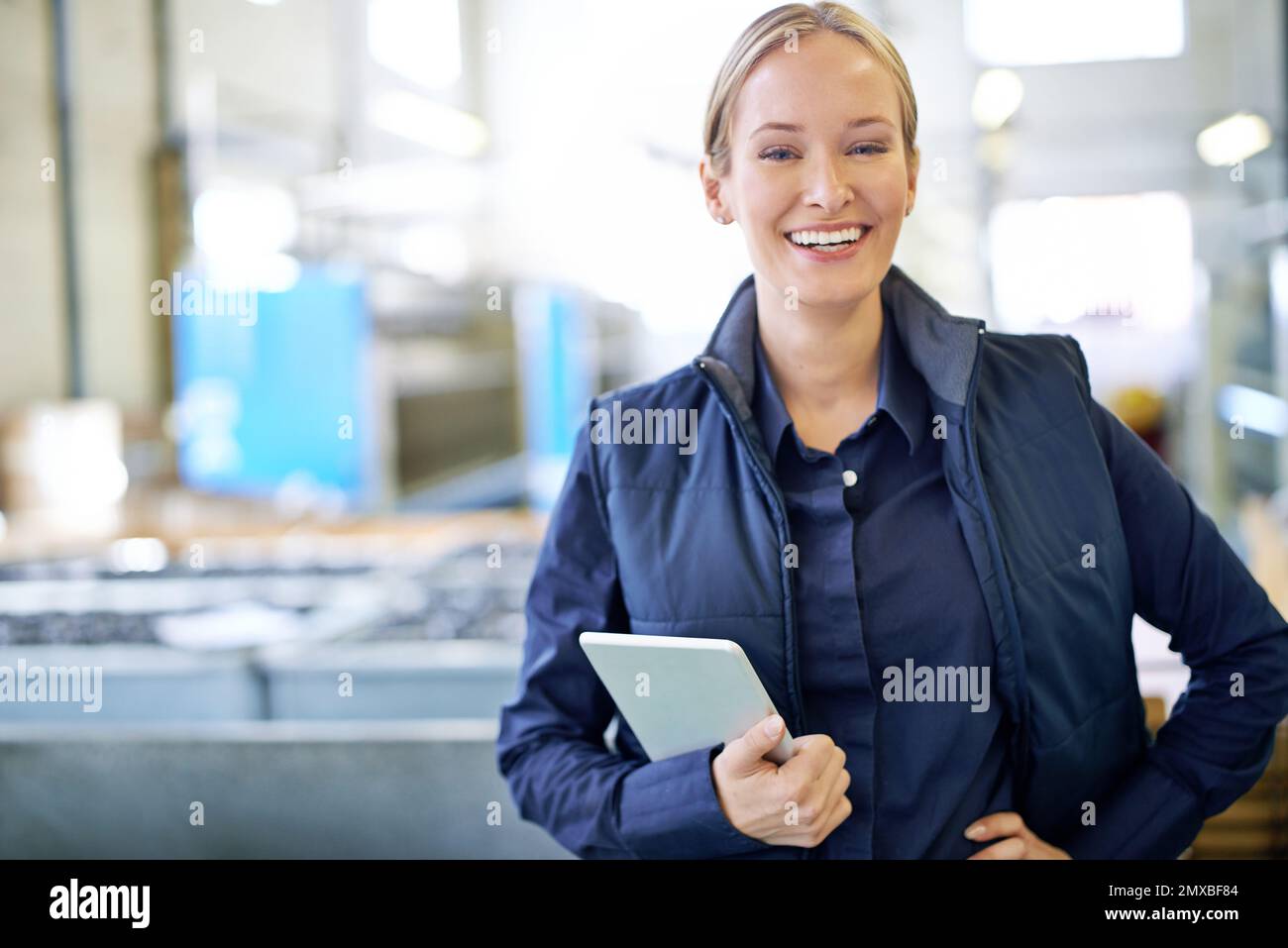 In charge on the factory floor. Portrait of a smiling manager holding a ...