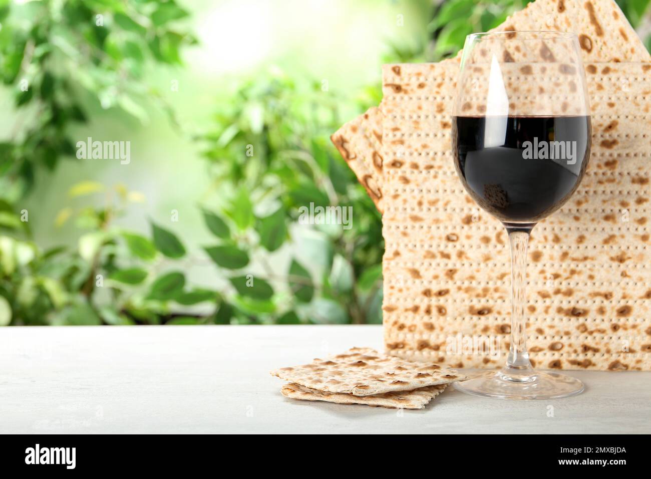 Traditional Matzos and glass of wine on white wooden table, space for