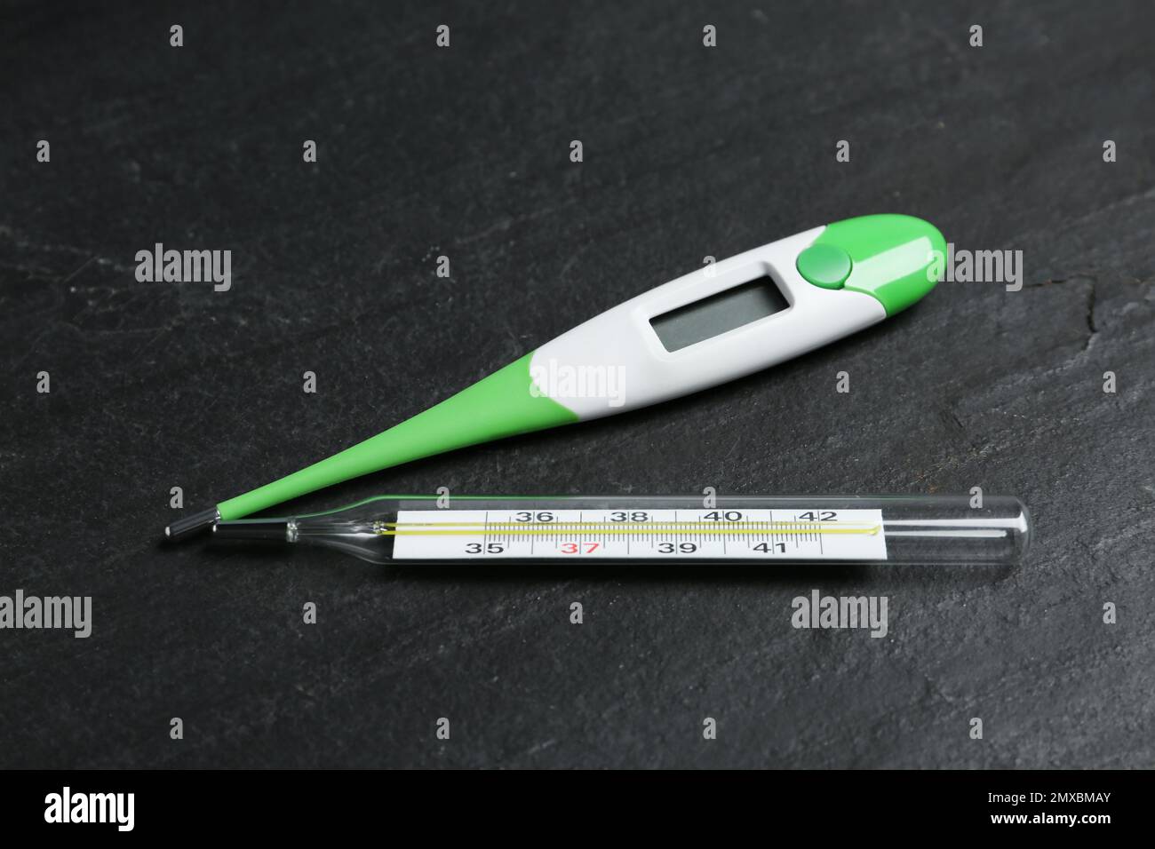 Mercury and digital thermometers on black slate background Stock Photo