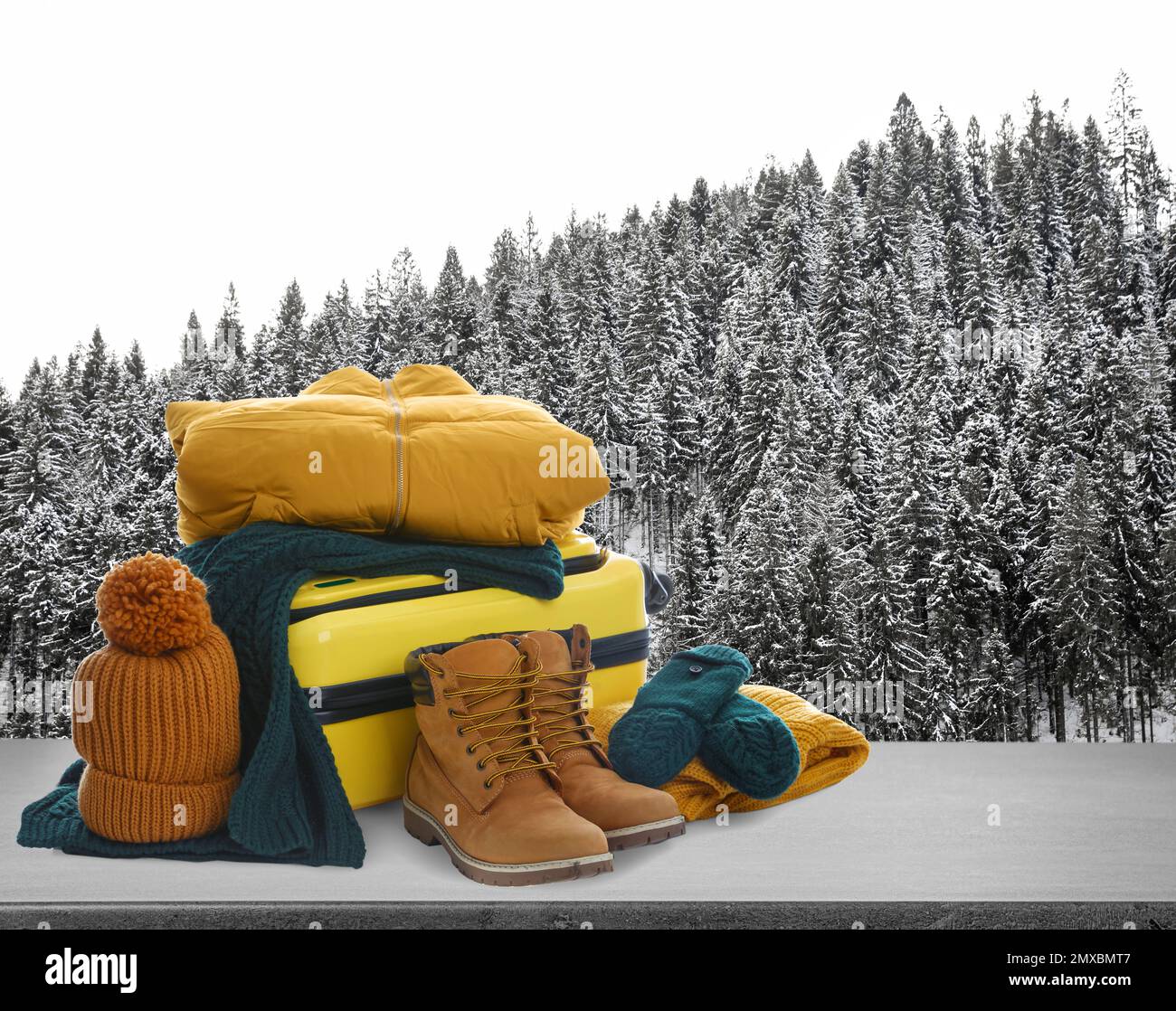 Suitcase with warm clothes on stone surface against beautiful winter