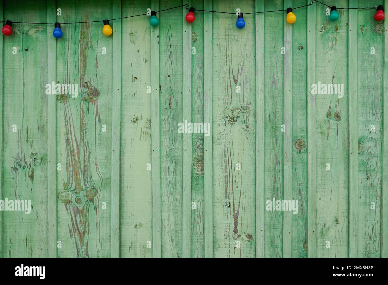 Background green weathered wooden fence planks and garland of bright