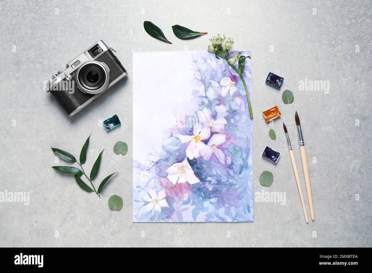 Flat lay composition with watercolor paints and floral picture on grey stone table Stock Photo
