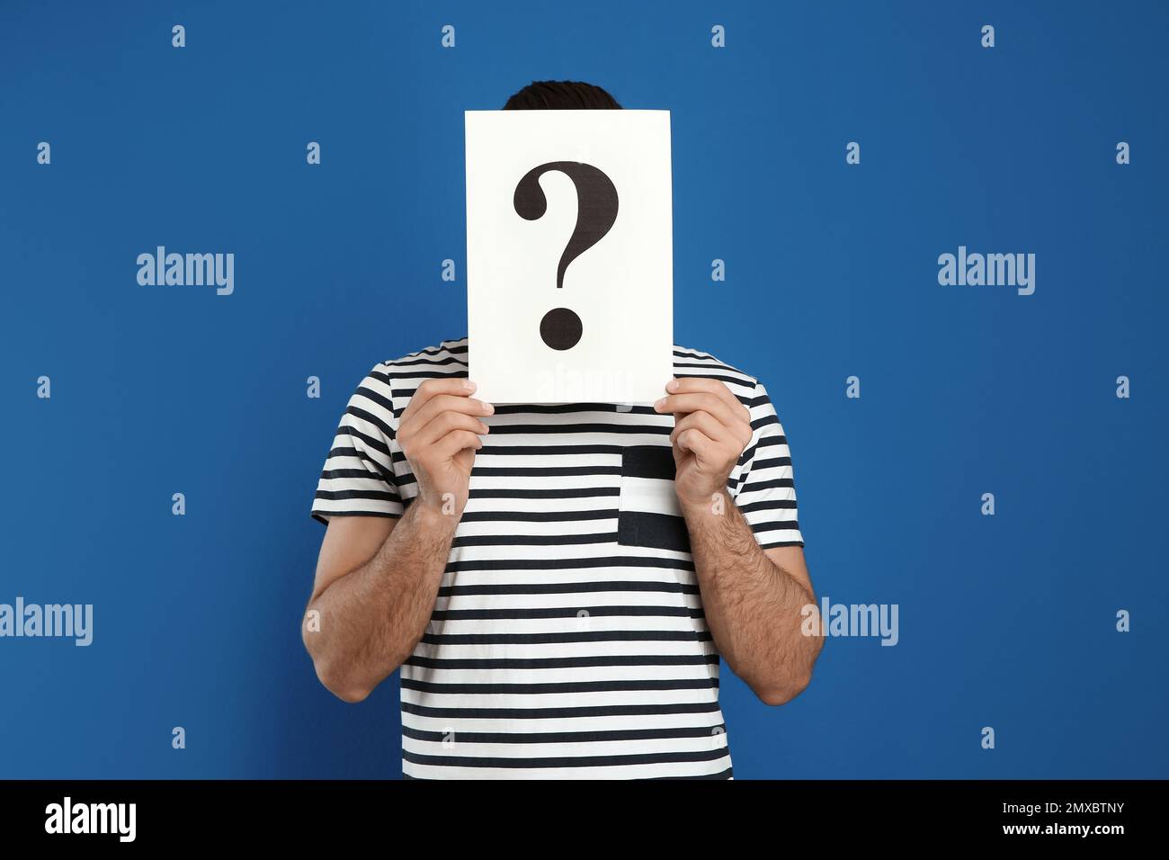Man holding question mark sign on blue background Stock Photo - Alamy