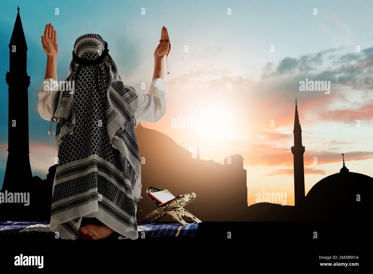 Muslim man praying and silhouette of mosque on background Stock Photo ...
