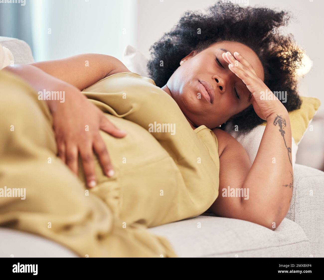 Pregnant, tired and black woman on sofa with headache pain in living room with hands on stomach