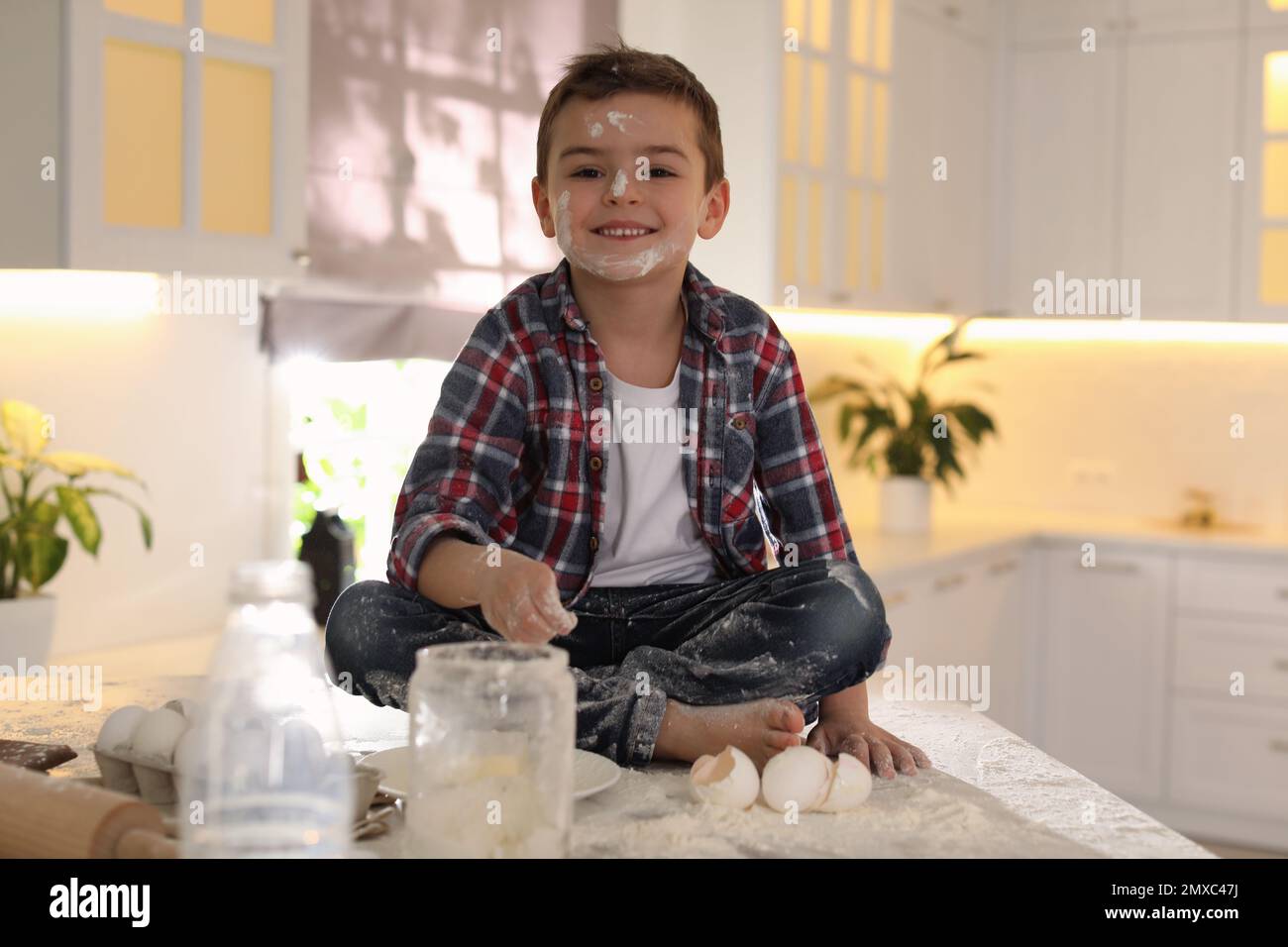 Cute little boy with flour on face in kitchen. Cooking dough Stock Photo