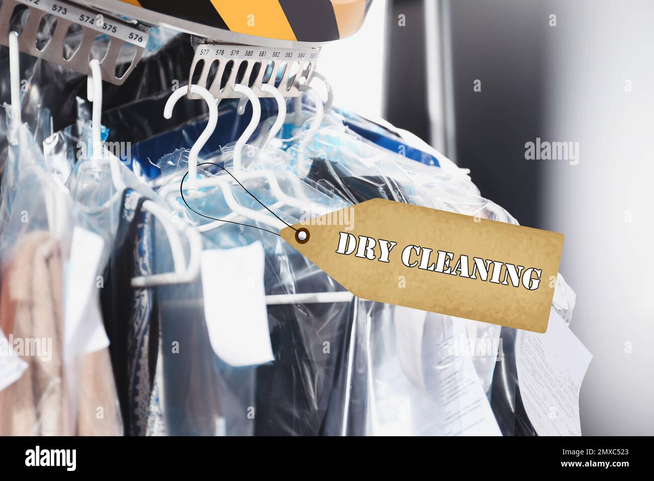Hangers with clothes on garment conveyor at drycleaner's, closeup