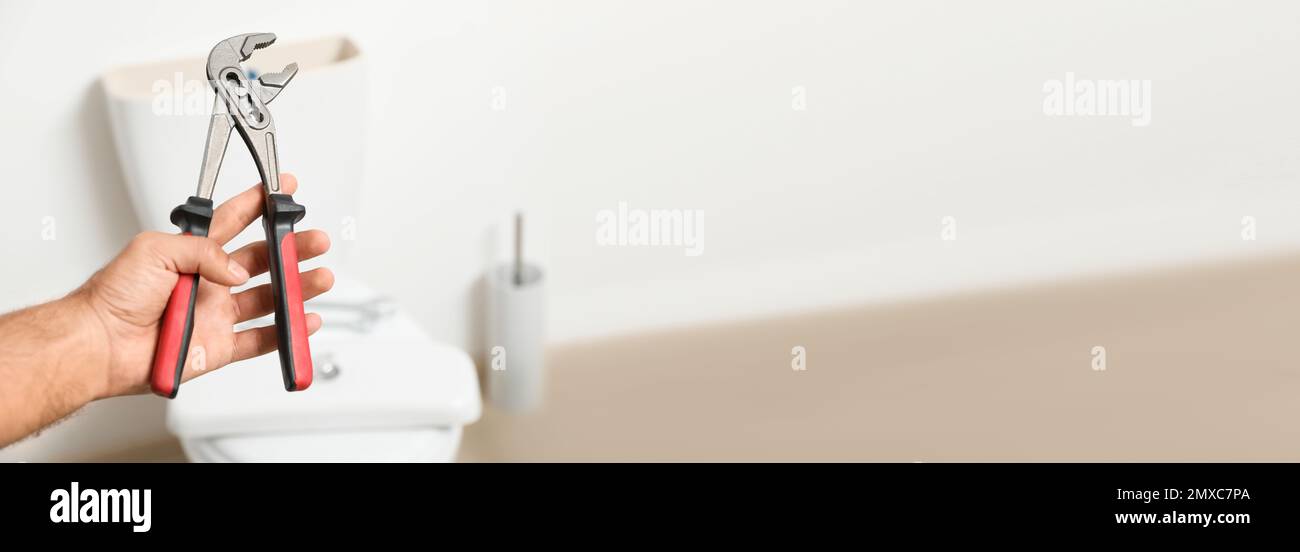 Closeup view of professional plumber holding pliers against toilet bowl