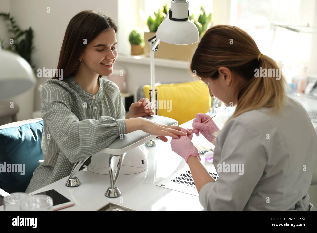 Professional manicurist working with client in beauty salon Stock Photo ...