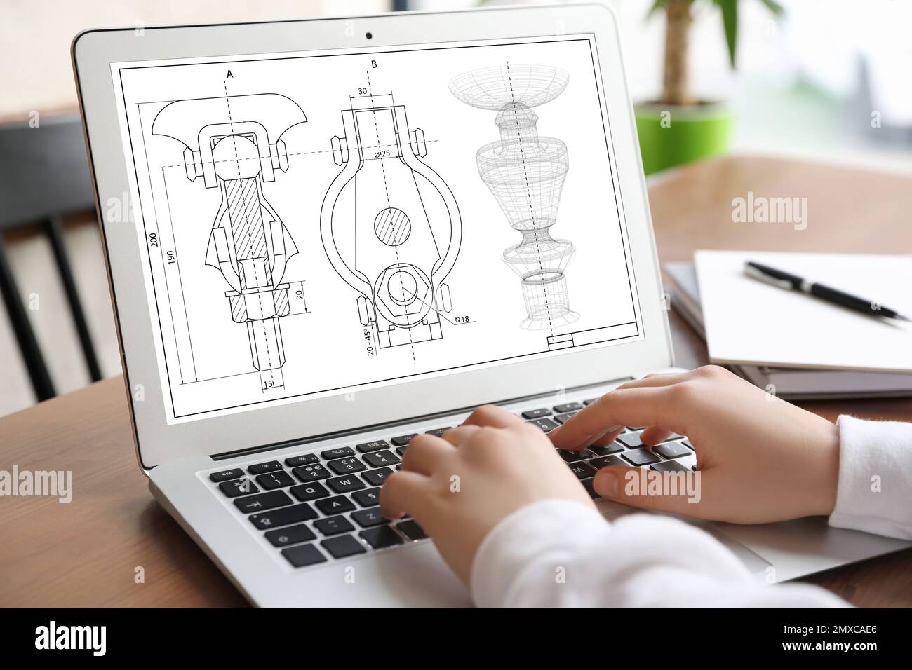 Female engineer working with technical drawing on laptop indoors, closeup Stock Photo