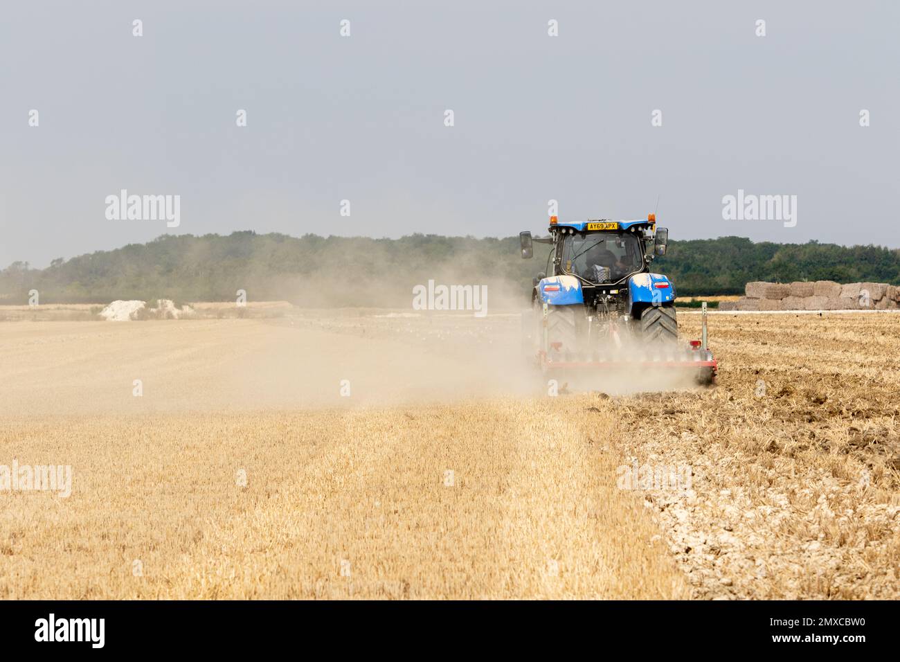 In Parham rural Suffolk a harrowing blue tractor making a drifting dust