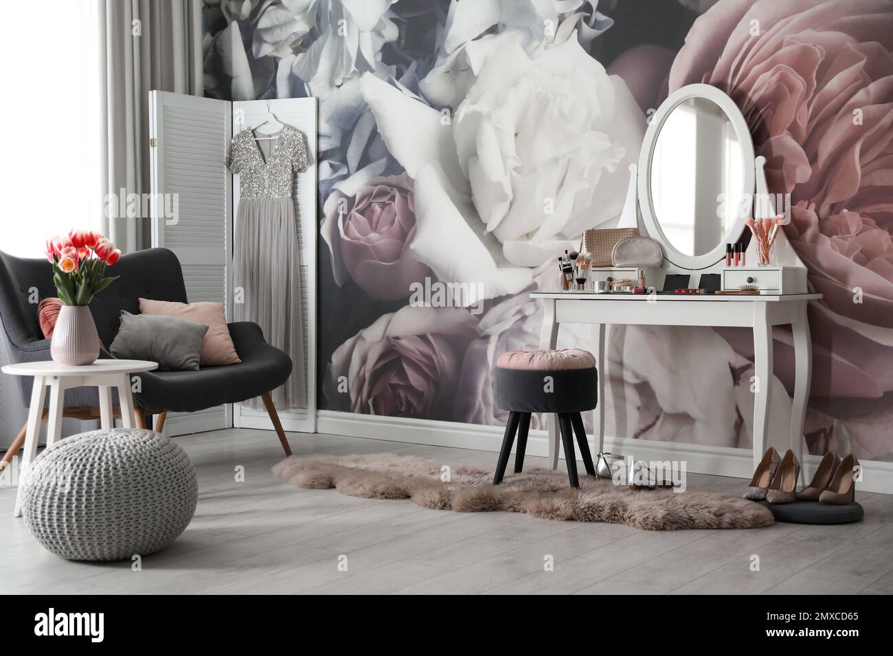 Stylish room interior with elegant dressing table, sofa and floral