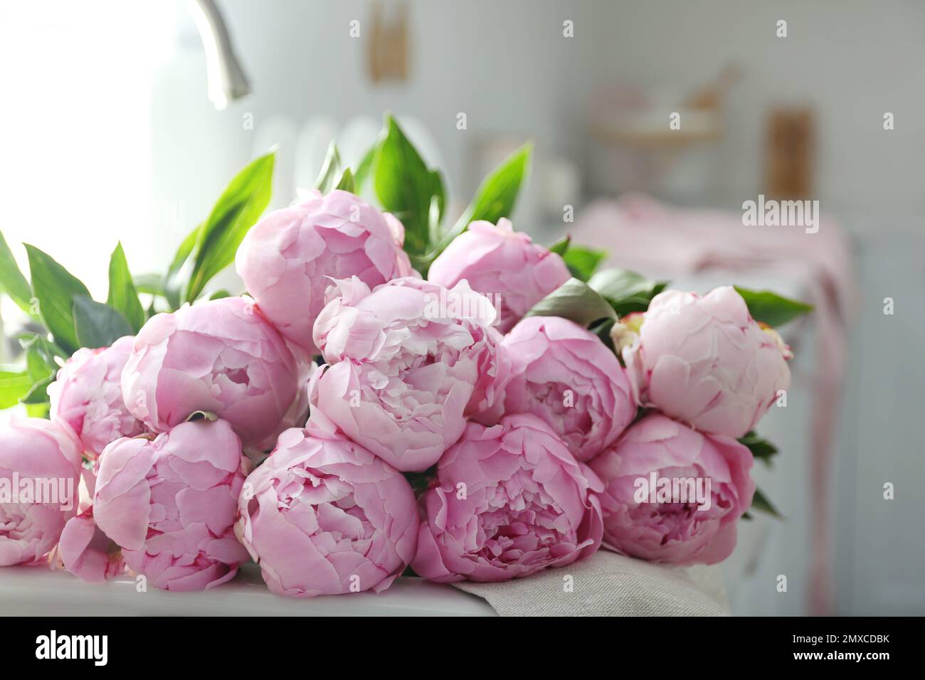 Bouquet of beautiful pink peonies on counter in kitchen Stock Photo