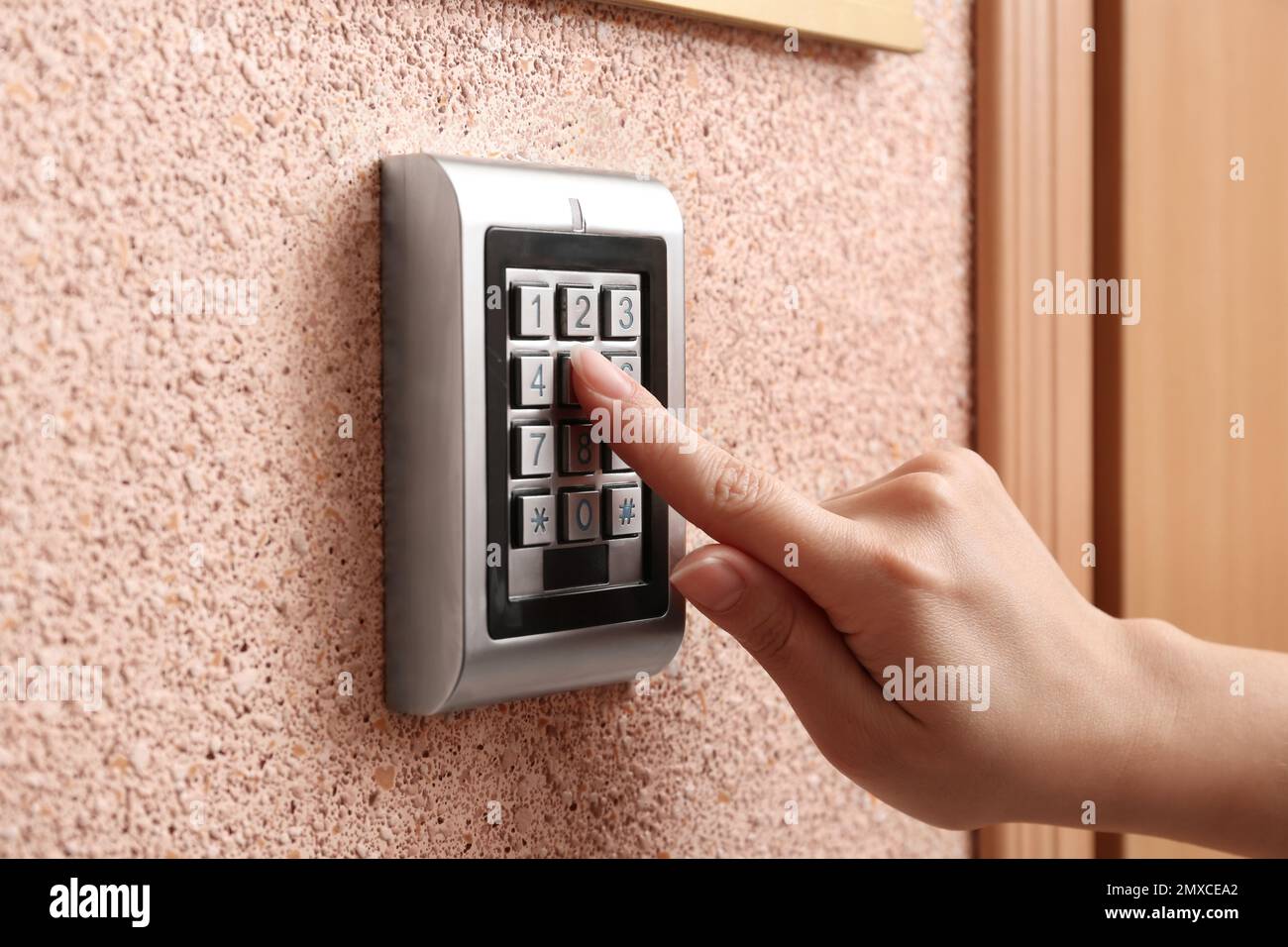 Woman entering code on electronic lock's keypad indoors, closeup Stock Photo