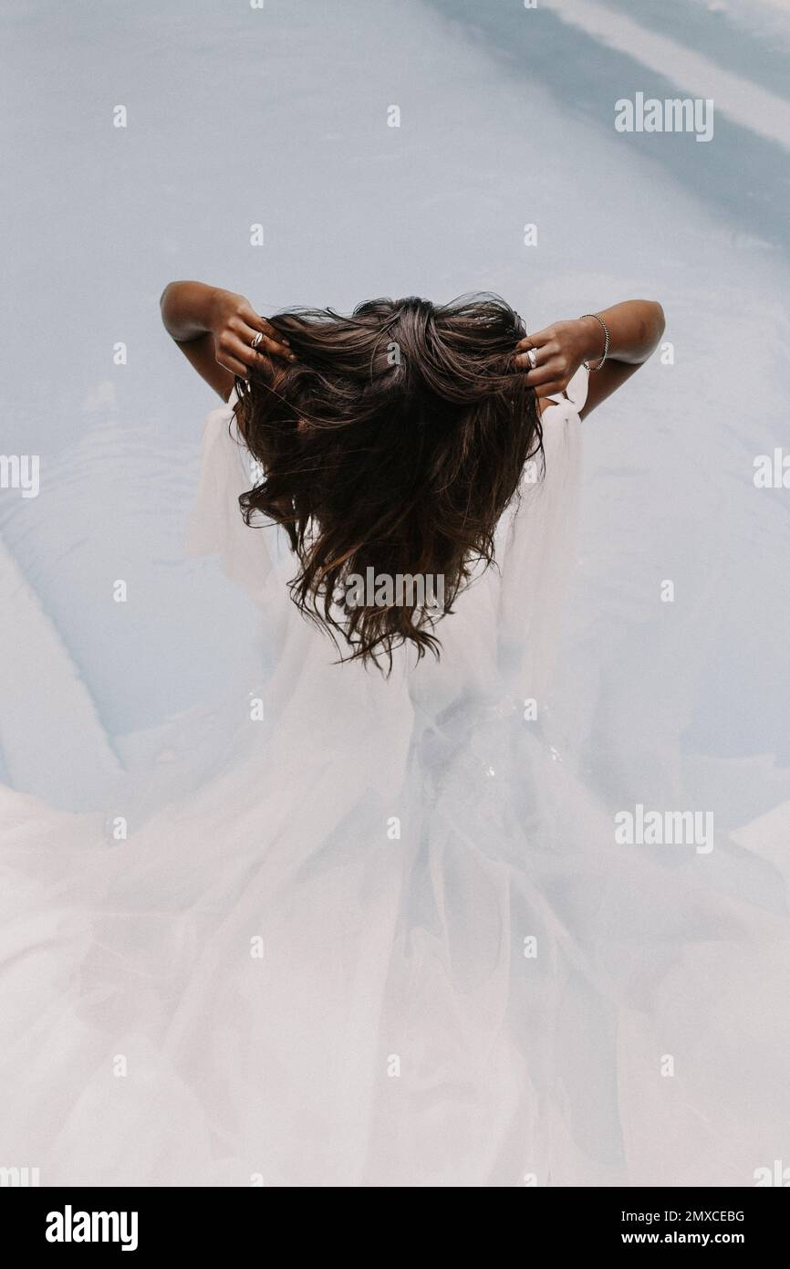 A back view of a bride wearing an elegant white wedding dress while ...