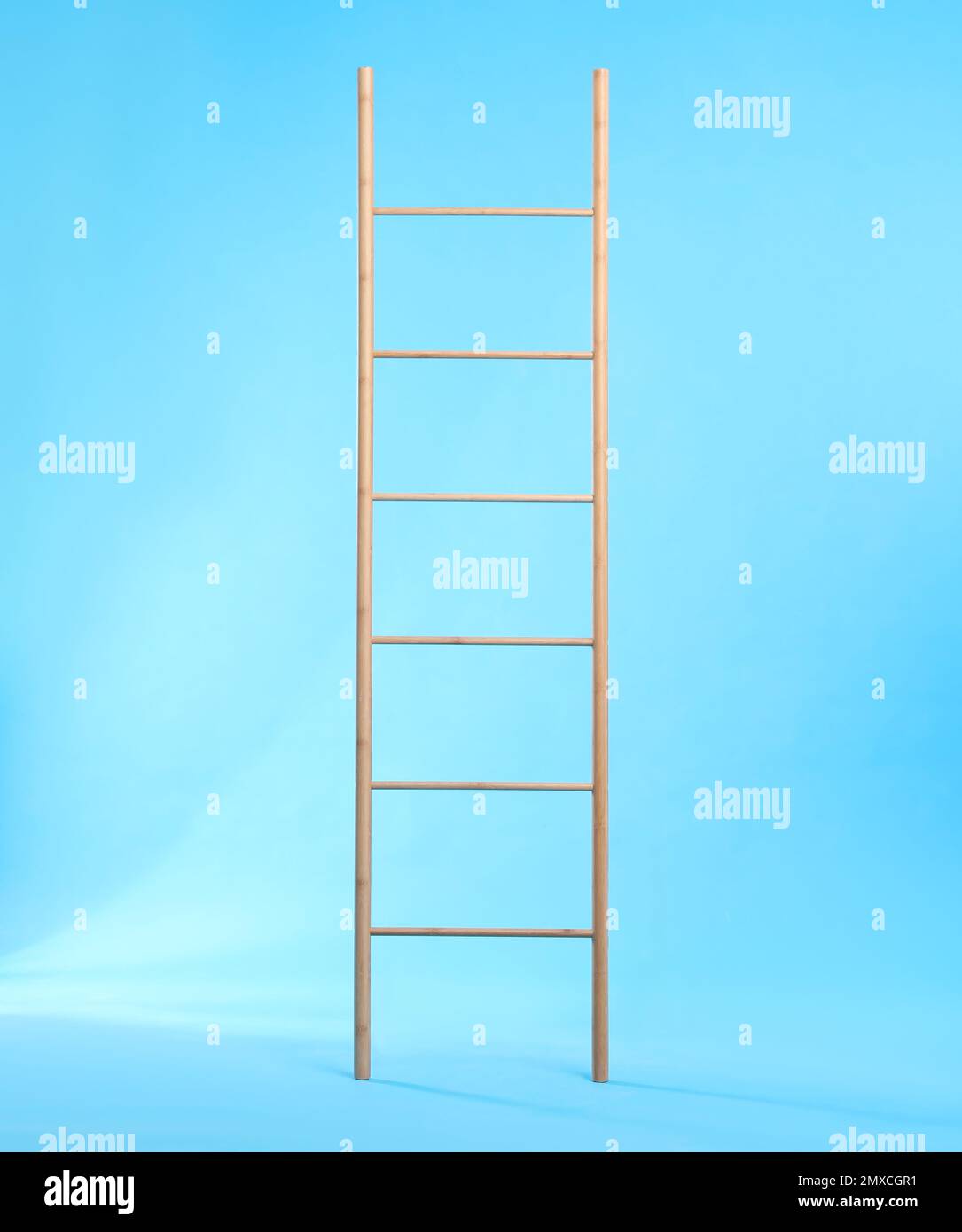 Modern wooden ladder on light blue background Stock Photo - Alamy