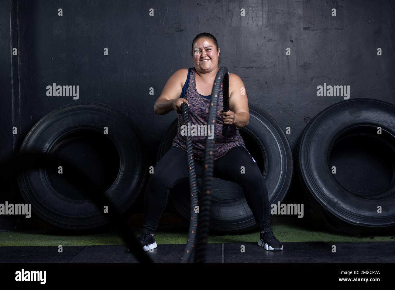 a Mexican overweight woman smiling while working out on cross fit gym Stock Photo