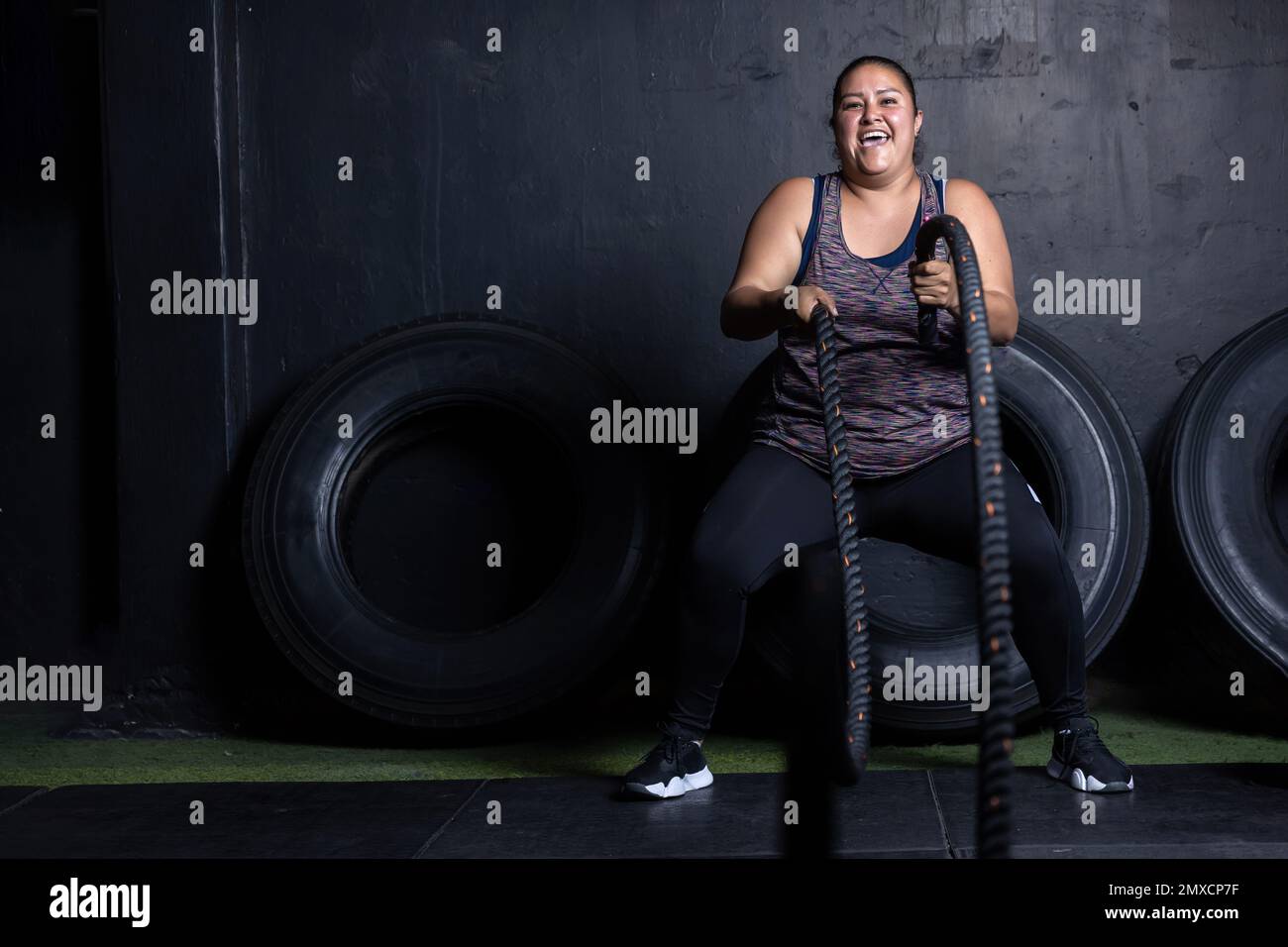a Mexican overweight woman smiling while working out on cross fit gym Stock Photo
